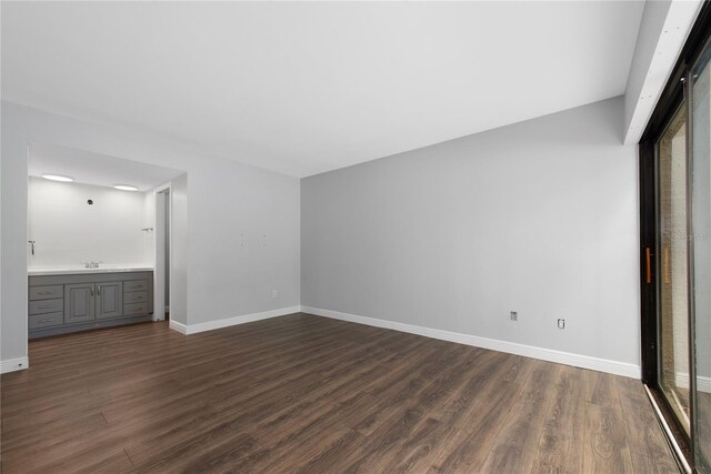 782 Village Lake Ter N Unit 102, Saint Petersburg, FL 33716 - unfurnished living room featuring dark wood-style floors, baseboards, and a sink