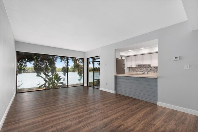 782 Village Lake Ter N Unit 102, Saint Petersburg, FL 33716 - unfurnished living room with dark wood-style flooring, baseboards, and a water view