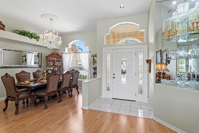 foyer featuring baseboards, a notable chandelier, and light wood-style flooring