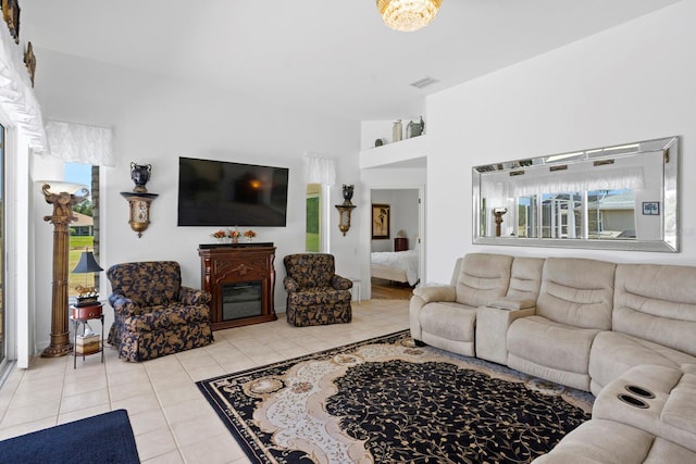 living room featuring light tile patterned flooring, visible vents, and a fireplace