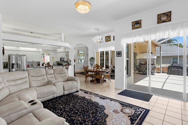 living room featuring light tile patterned floors, plenty of natural light, a notable chandelier, and arched walkways