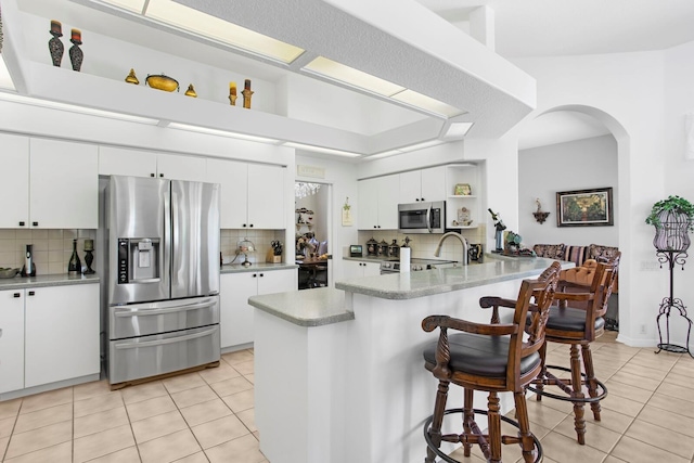 kitchen with light tile patterned floors, stainless steel appliances, and backsplash