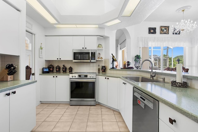 kitchen featuring a sink, stainless steel appliances, a notable chandelier, tasteful backsplash, and white cabinetry
