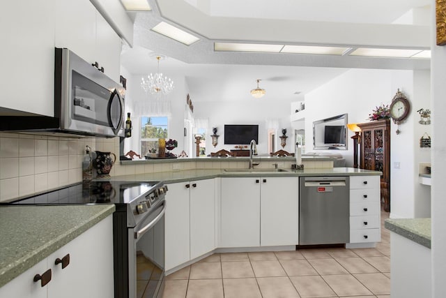 kitchen with a sink, a notable chandelier, backsplash, appliances with stainless steel finishes, and open floor plan