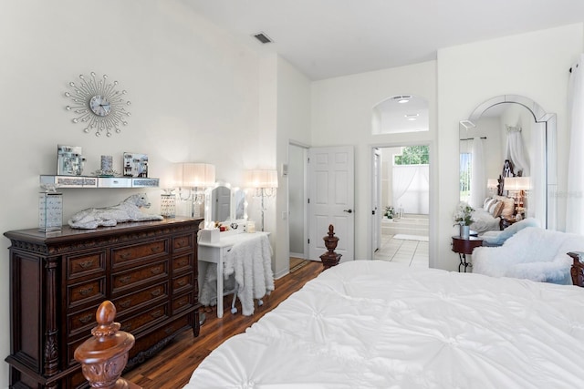 bedroom with visible vents, wood finished floors, connected bathroom, and arched walkways