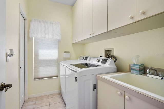 laundry room with a sink, cabinet space, washing machine and clothes dryer, light tile patterned floors, and baseboards