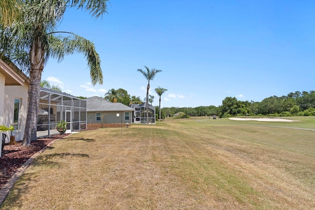 view of yard with a lanai and view of golf course
