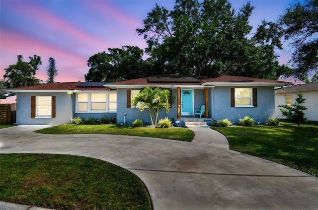 6207 Gulfport Blvd S, Gulfport, FL 33707 - ranch-style home featuring solar panels, a lawn, stucco siding, and curved driveway