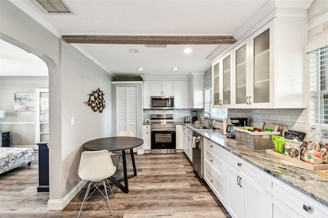 6207 Gulfport Blvd S, Gulfport, FL 33707 - kitchen featuring a sink, tasteful backsplash, white cabinetry, light wood-style floors, and appliances with stainless steel finishes
