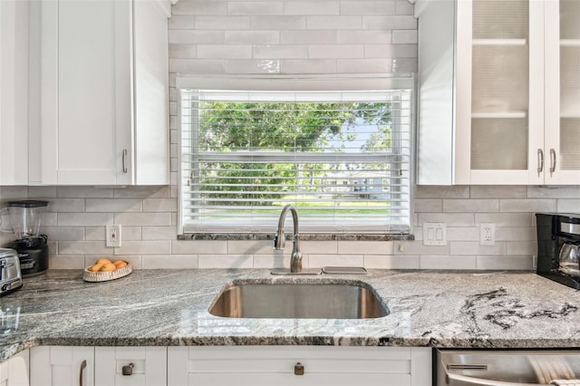 6207 Gulfport Blvd S, Gulfport, FL 33707 - kitchen featuring white cabinets, backsplash, stainless steel dishwasher, a sink, and light stone countertops