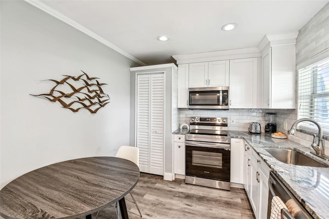 6207 Gulfport Blvd S, Gulfport, FL 33707 - kitchen with white cabinets, light stone countertops, appliances with stainless steel finishes, and a sink