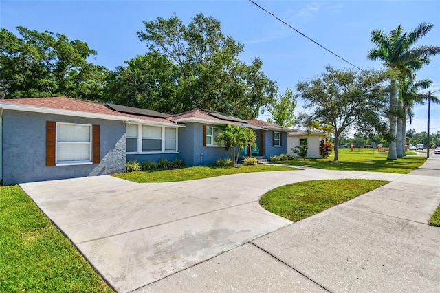 6207 Gulfport Blvd S, Gulfport, FL 33707 - ranch-style home with roof mounted solar panels, a front yard, stucco siding, and curved driveway
