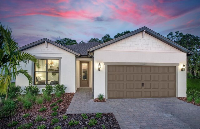 ranch-style house featuring stucco siding, decorative driveway, and a garage