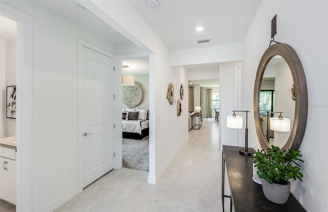corridor with visible vents, baseboards, and light tile patterned floors