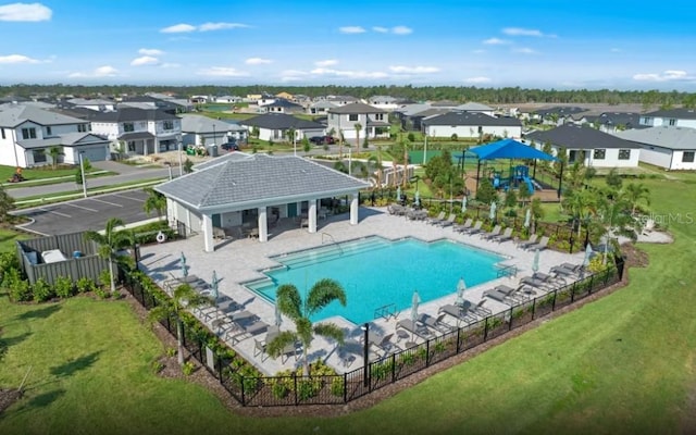 community pool with fence, a yard, and a residential view