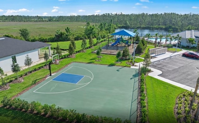 view of basketball court featuring a lawn, a forest view, playground community, and community basketball court