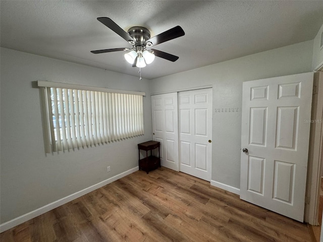 6047 67th Ave N, Pinellas Park, FL 33781 - unfurnished bedroom featuring a textured ceiling, baseboards, a closet, and wood finished floors
