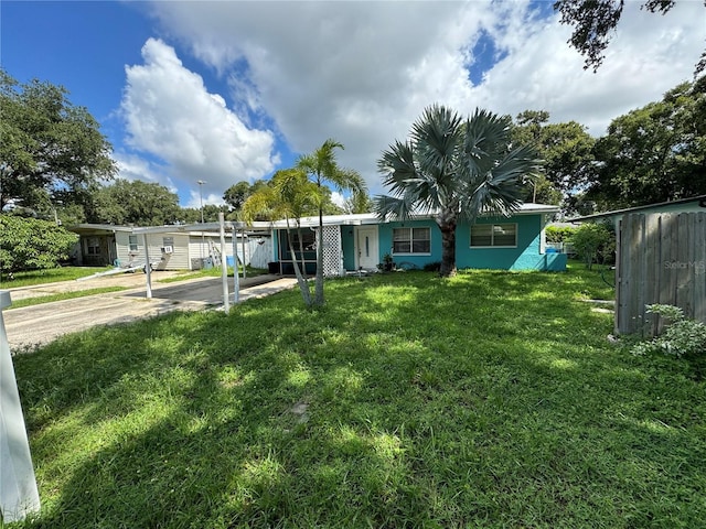 6047 67th Ave N, Pinellas Park, FL 33781 - view of front facade with concrete driveway, fence, a carport, and a front lawn