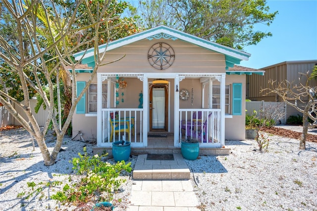 view of front of home featuring a porch, fence, and stucco siding