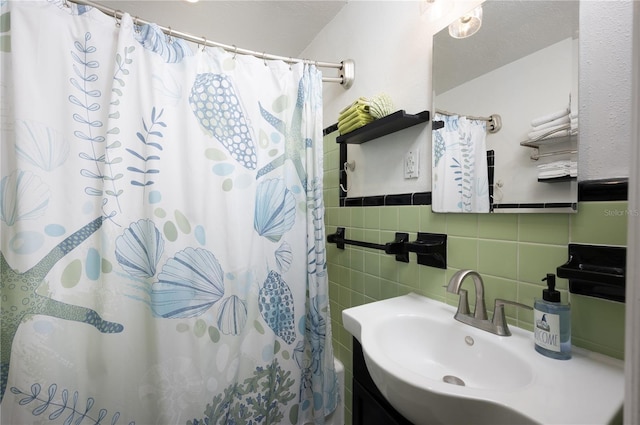 bathroom with a shower with shower curtain, tile walls, and a sink