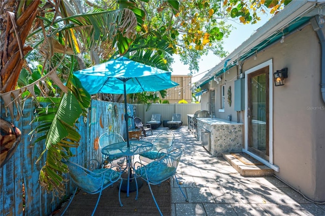 view of patio / terrace featuring outdoor dining area, a fenced backyard, and an outdoor kitchen