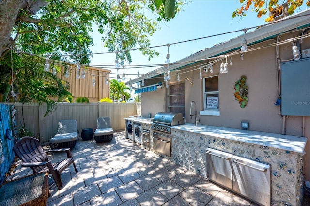 view of patio / terrace featuring fence, a sink, exterior kitchen, and area for grilling