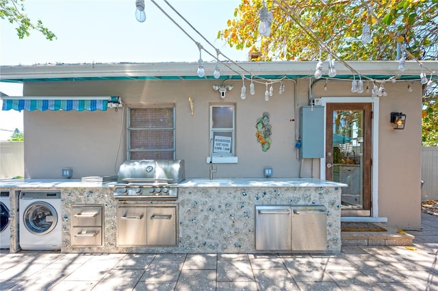 view of patio featuring separate washer and dryer, a sink, an outdoor kitchen, and area for grilling