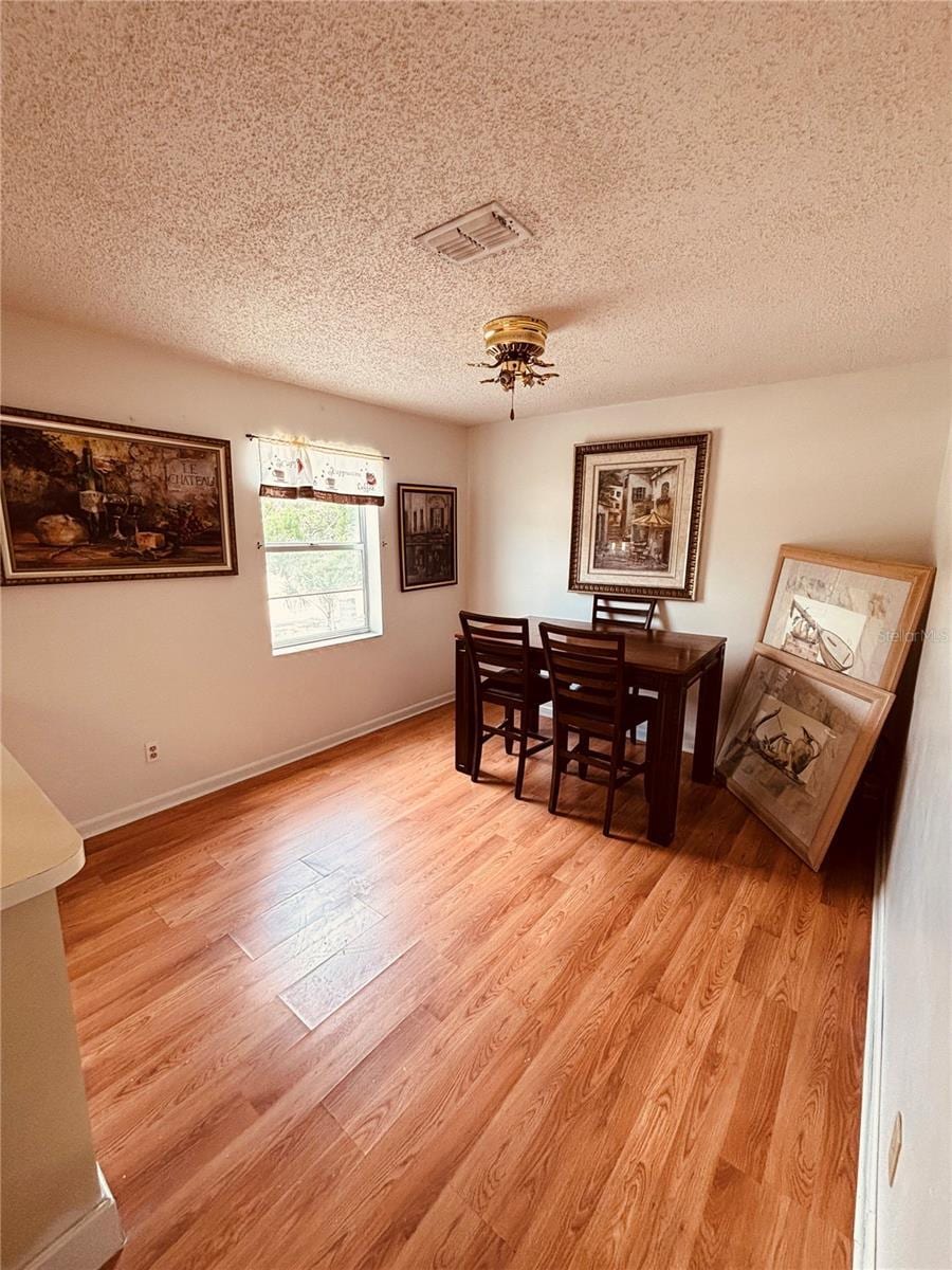 dining area featuring a textured ceiling, visible vents, and light wood-style floors