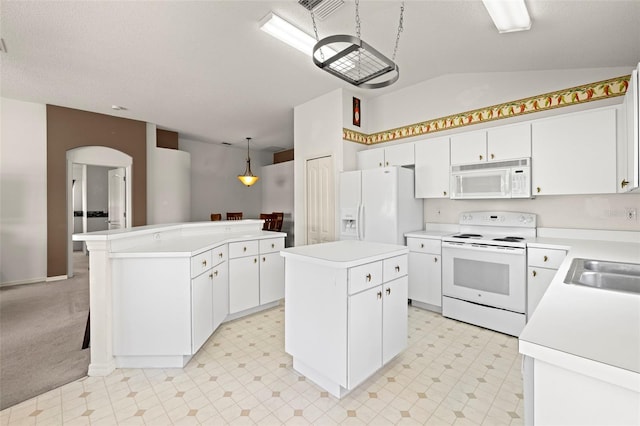kitchen with white appliances, a center island, light countertops, arched walkways, and vaulted ceiling
