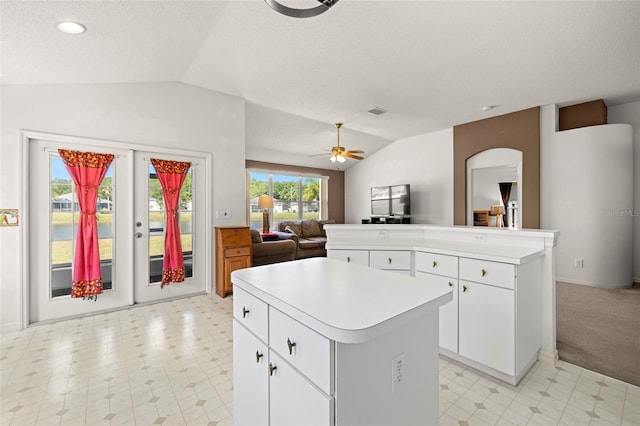 kitchen featuring a ceiling fan, a kitchen island, light countertops, open floor plan, and lofted ceiling