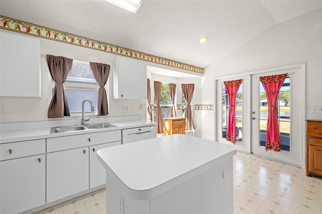 kitchen with plenty of natural light, a sink, light floors, and vaulted ceiling