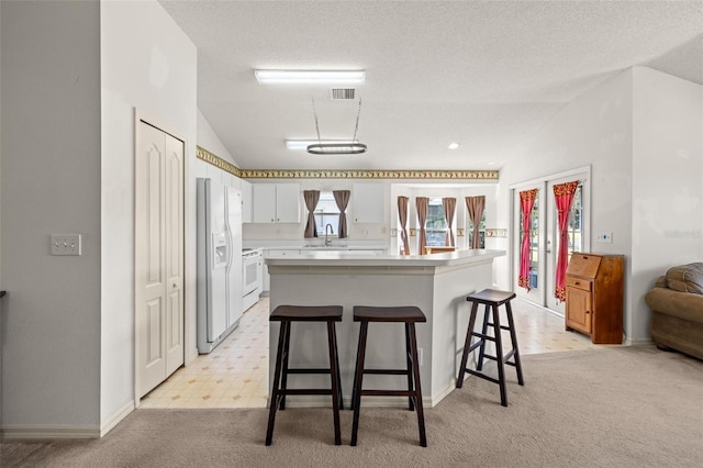 kitchen featuring visible vents, vaulted ceiling, light countertops, a sink, and white appliances