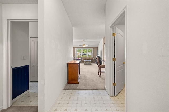 corridor with light floors, baseboards, and light colored carpet