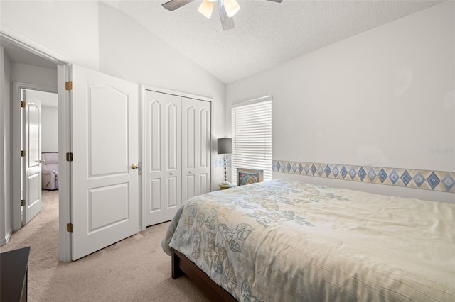 bedroom featuring a ceiling fan, a textured ceiling, vaulted ceiling, carpet floors, and a closet