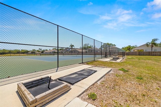 view of sport court with a yard and fence
