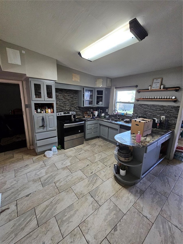 3714 E Ellicott St, Tampa, FL 33610 - kitchen with open shelves, backsplash, gray cabinetry, stainless steel electric stove, and glass insert cabinets