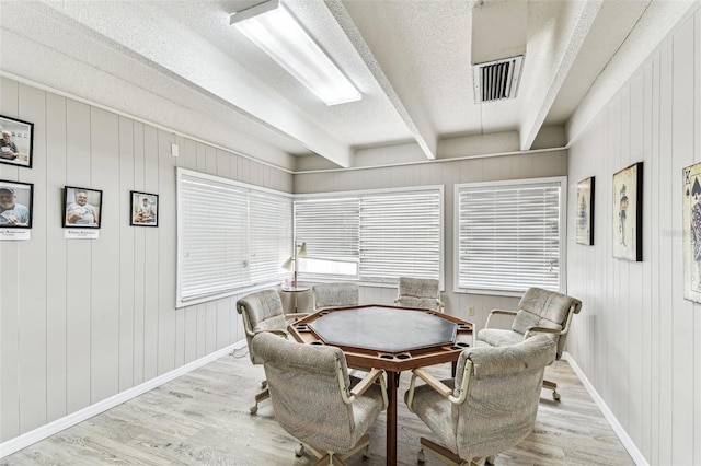 9945 47th Ave N Unit 208, Saint Petersburg, FL 33708 - dining space with wood finished floors, a textured ceiling, beamed ceiling, baseboards, and wooden walls