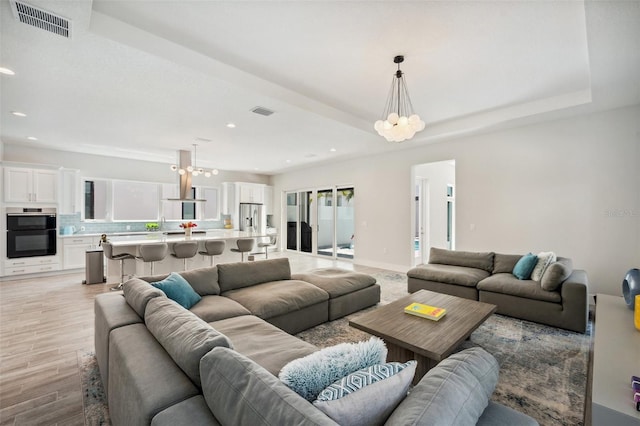 5917 Cat Claw Ln, Bradenton, FL 34210 - living area featuring light wood finished floors, visible vents, and a notable chandelier