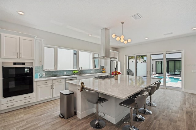5917 Cat Claw Ln, Bradenton, FL 34210 - kitchen featuring a center island, tasteful backsplash, appliances with stainless steel finishes, light wood finished floors, and white cabinetry