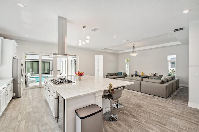 5917 Cat Claw Ln, Bradenton, FL 34210 - kitchen with island range hood, stainless steel appliances, visible vents, and a raised ceiling