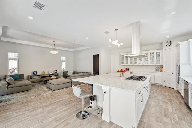 5917 Cat Claw Ln, Bradenton, FL 34210 - kitchen with white cabinets, island exhaust hood, open floor plan, light wood-style floors, and appliances with stainless steel finishes