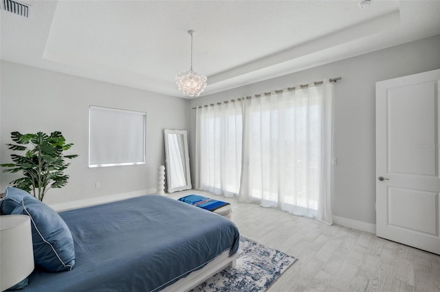 5917 Cat Claw Ln, Bradenton, FL 34210 - bedroom featuring a tray ceiling, wood finished floors, visible vents, baseboards, and a notable chandelier