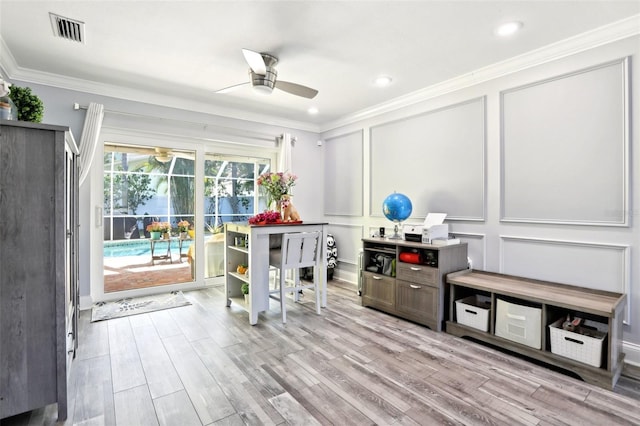 interior space featuring visible vents, a ceiling fan, crown molding, and a decorative wall
