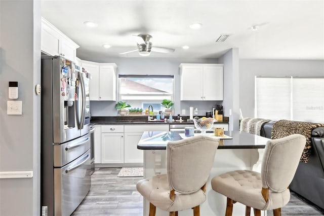 kitchen with light wood finished floors, a kitchen breakfast bar, white cabinets, and stainless steel fridge with ice dispenser