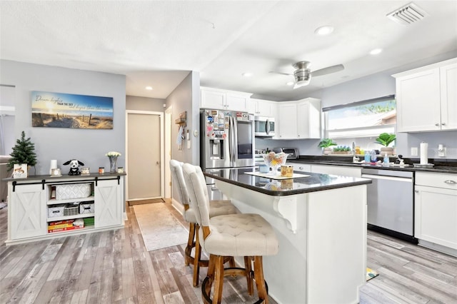 kitchen featuring a sink, ceiling fan, dark countertops, stainless steel appliances, and light wood-style floors