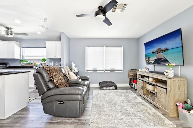 living area with wood finished floors, visible vents, and a ceiling fan