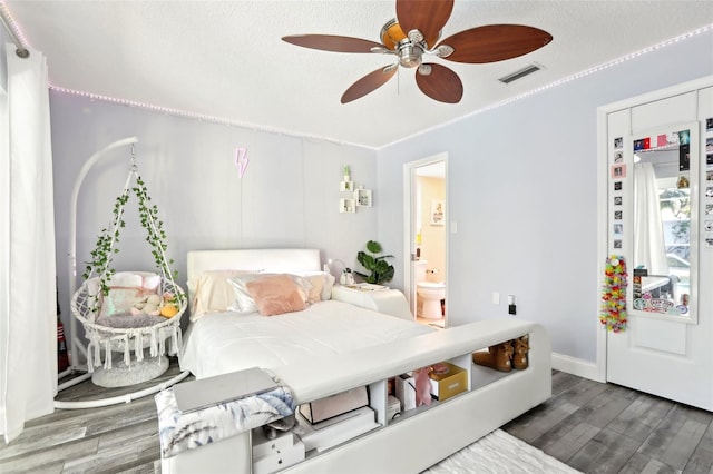 bedroom featuring baseboards, visible vents, wood finished floors, and a textured ceiling