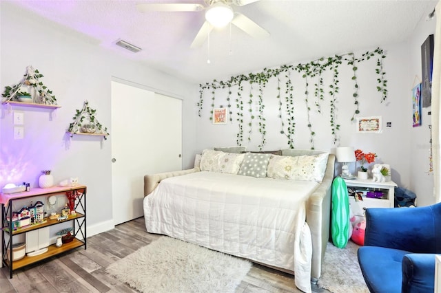 bedroom with a textured ceiling, wood finished floors, ceiling fan, and visible vents