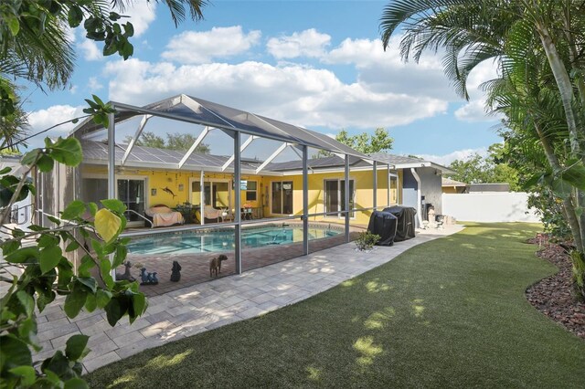rear view of house with a patio, a fenced in pool, stucco siding, a lawn, and fence