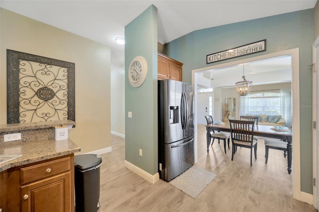 kitchen featuring stainless steel fridge with ice dispenser, baseboards, light wood-style flooring, a chandelier, and brown cabinetry